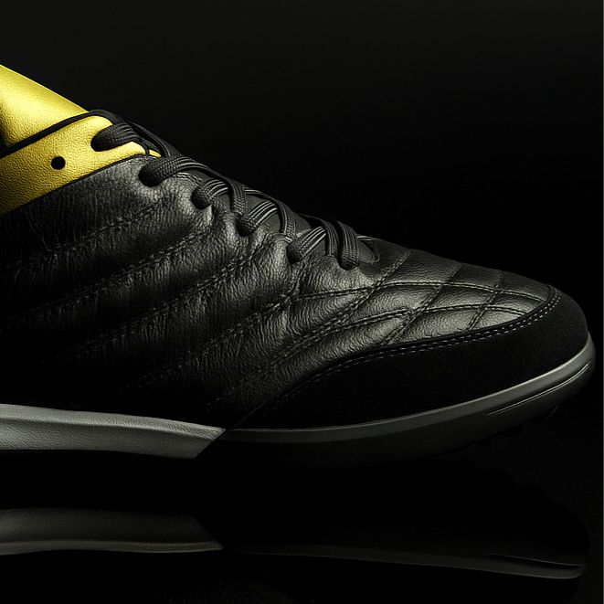 Black sneaker with gold accents on a black background